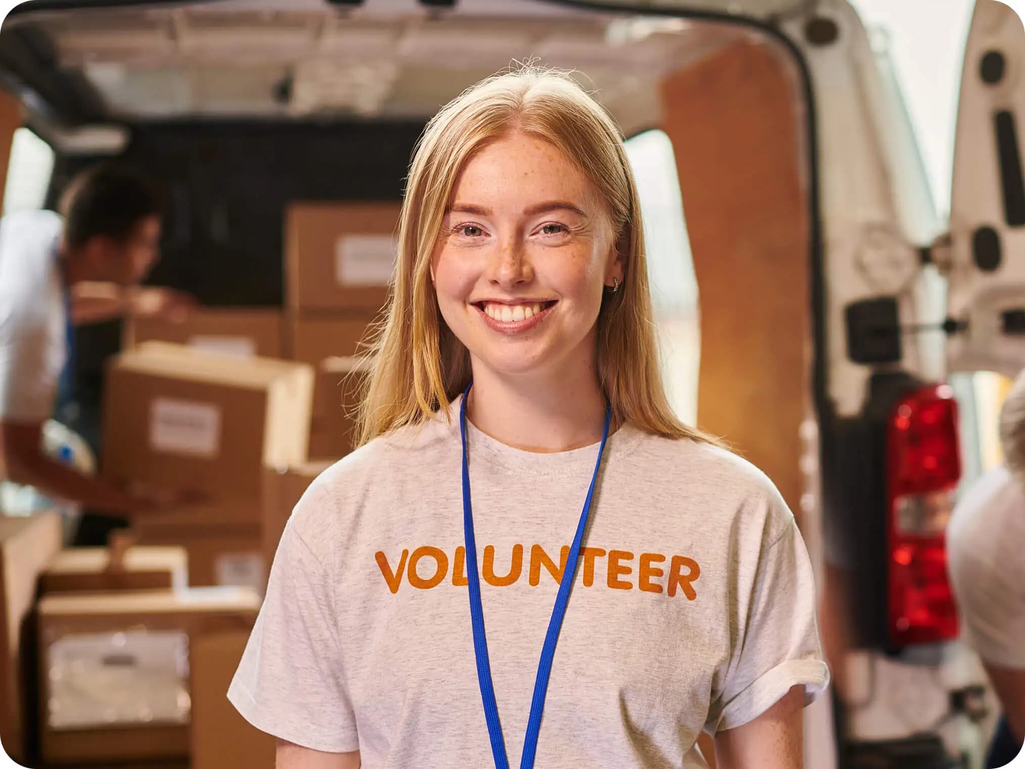 Young woman in a volunteer T-shirt and lanyard smiling warmly.
